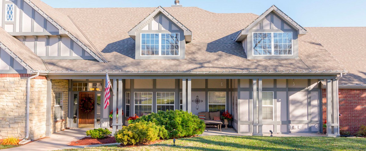 A suburban house with a front porch and an American flag displayed on the lawn.