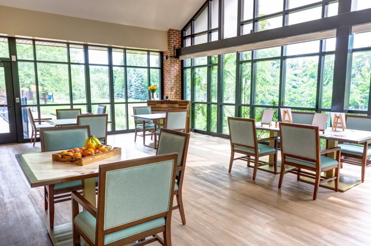 A bright and airy dining area featuring modern furniture and large windows allowing natural light to flood the space.