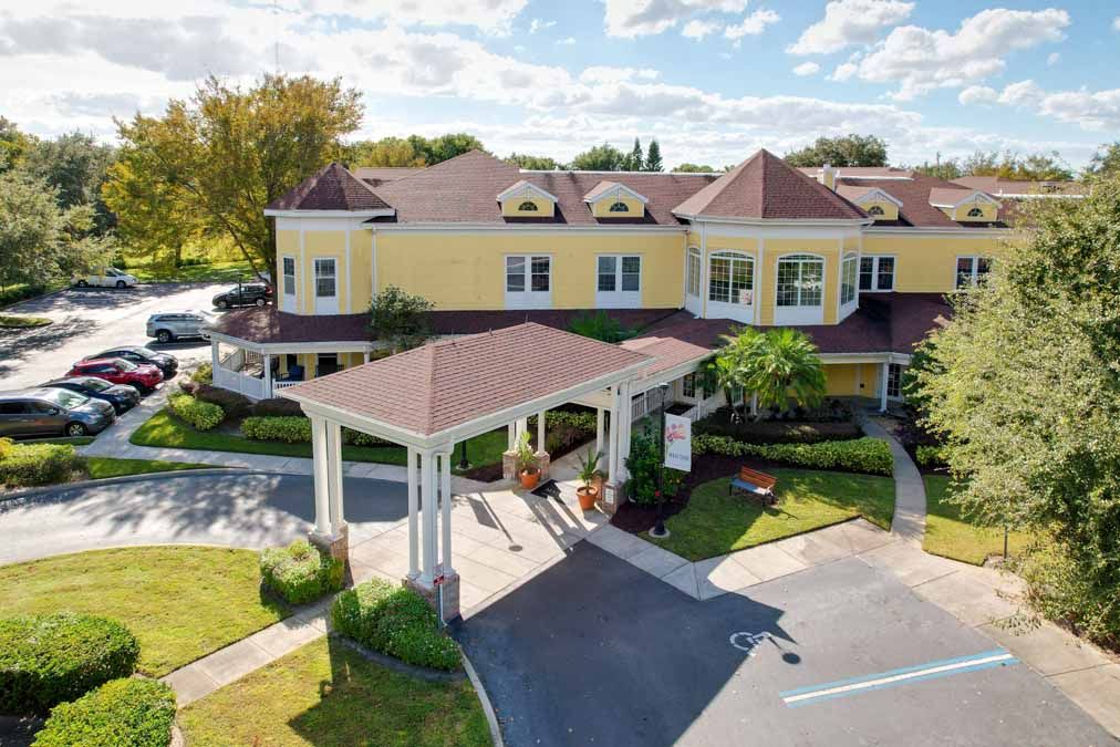 A charming yellow building with a covered entrance and landscaped surroundings under a blue sky.