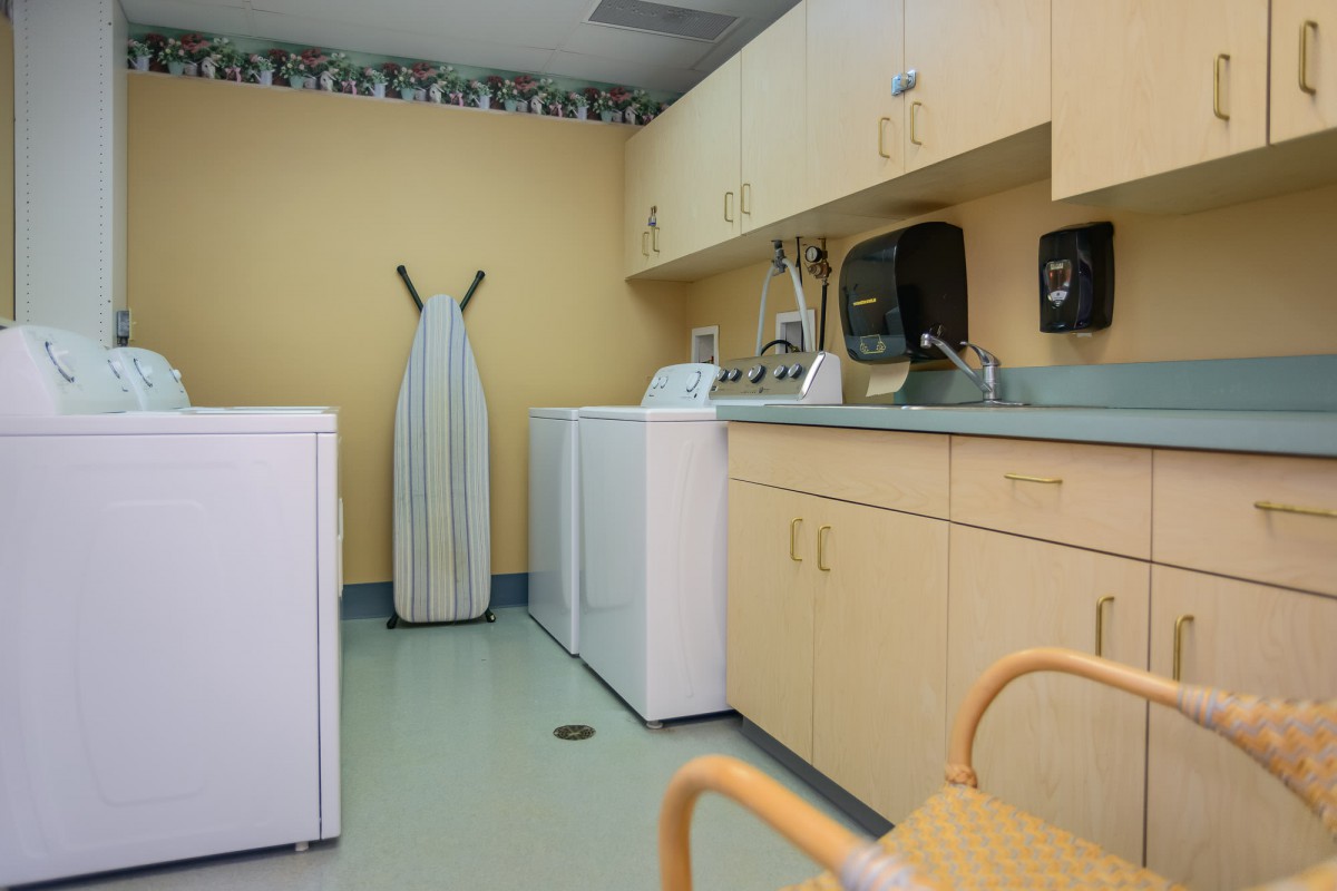 A well-organized laundry room with a washer, dryer, and ironing board.