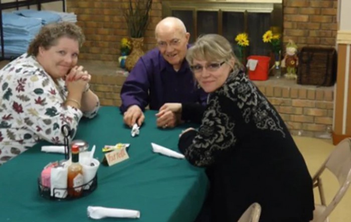 A group of people seated around a table indoors, engaging in a social gathering.