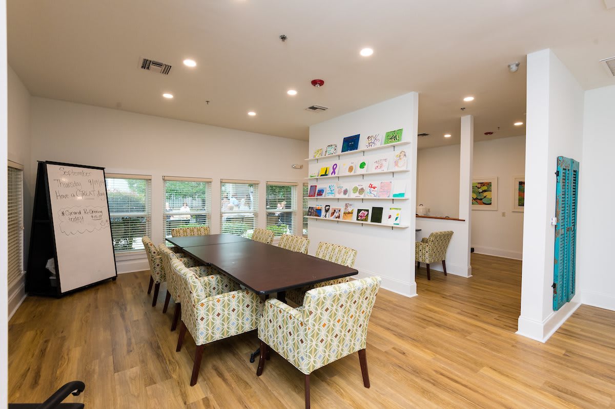 A modern conference room with a long table, comfortable chairs, and an art display on the wall.