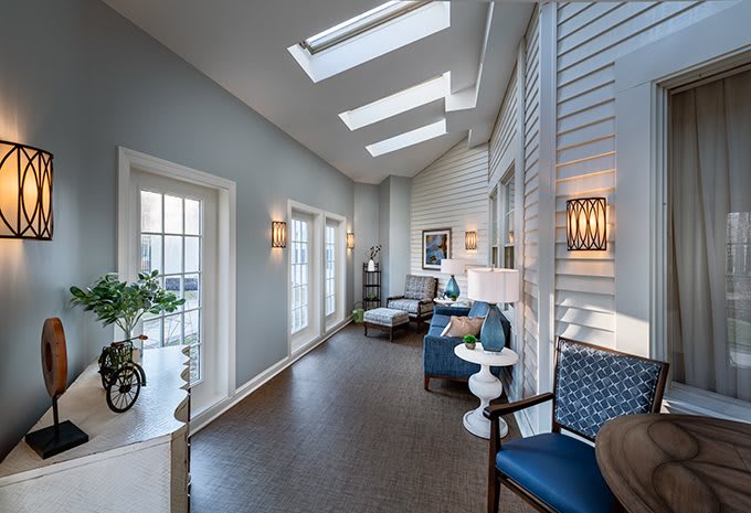A modern interior with skylights and a cozy seating area, featuring blue chairs and ample natural light.
