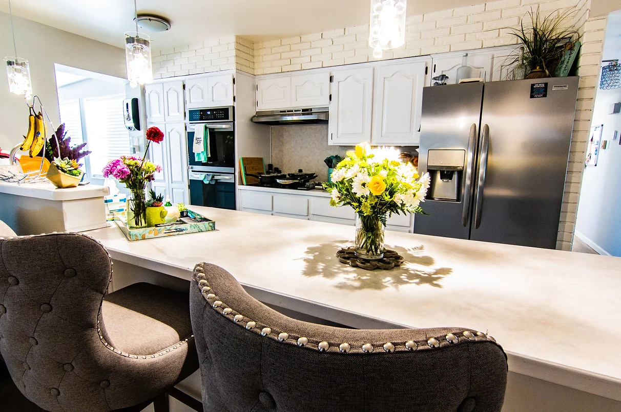 A modern kitchen with a central island adorned with flower arrangements and sleek appliances.