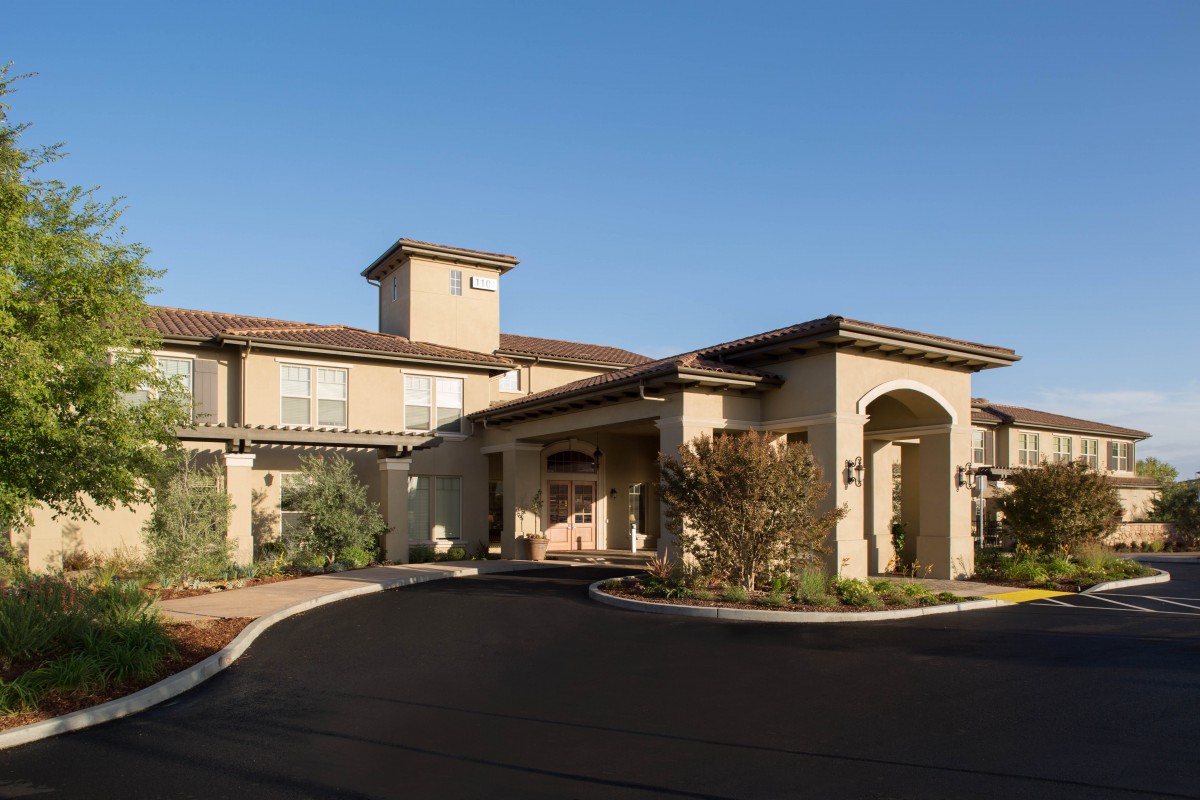 A residential building with a well-maintained driveway and landscaping under a clear blue sky.
