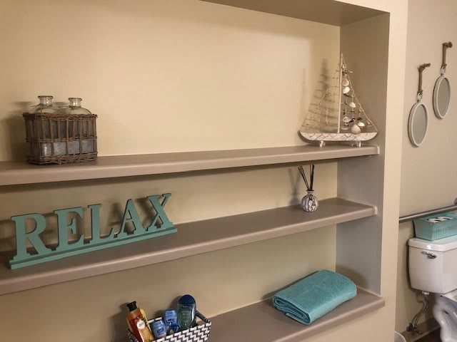 A neatly arranged shelf with decorative items, including a 'RELAX' sign and nautical ornaments.