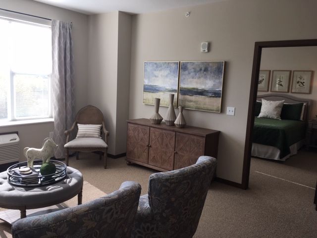 A cozy living room featuring elegant furniture and artwork, with natural light streaming through a window.