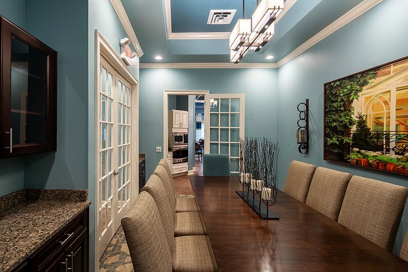A stylish dining room with blue walls and modern lighting.