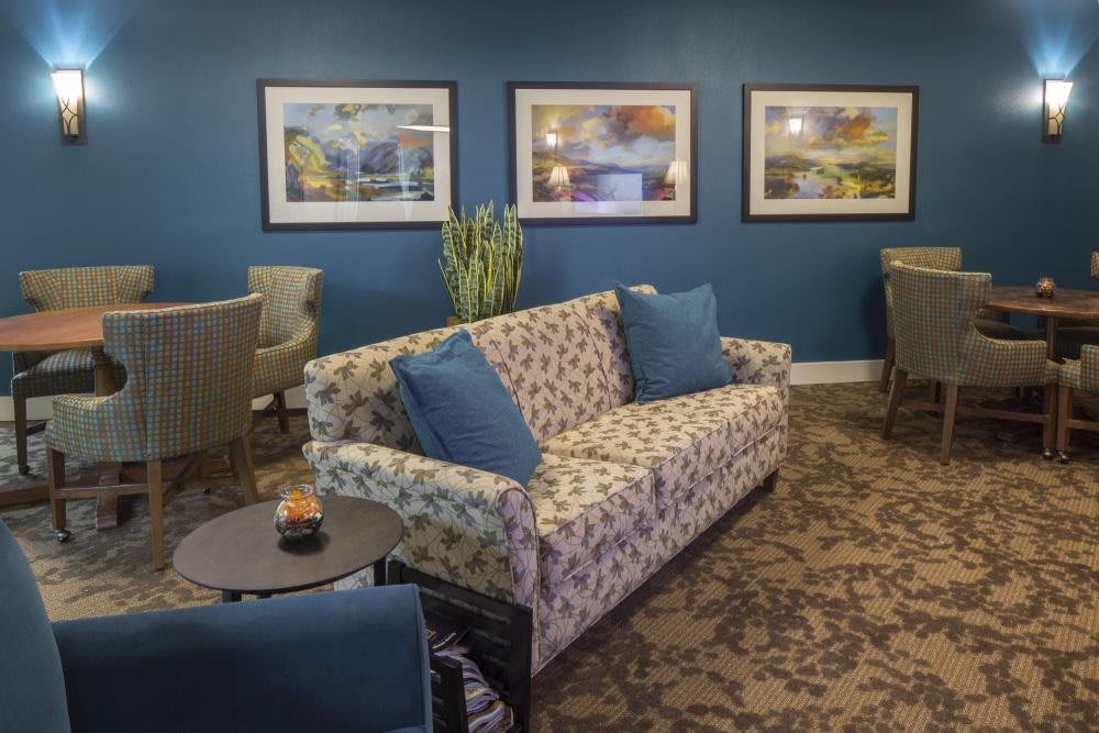 A cozy living room with a patterned sofa, blue cushions, and artwork on a blue accent wall.