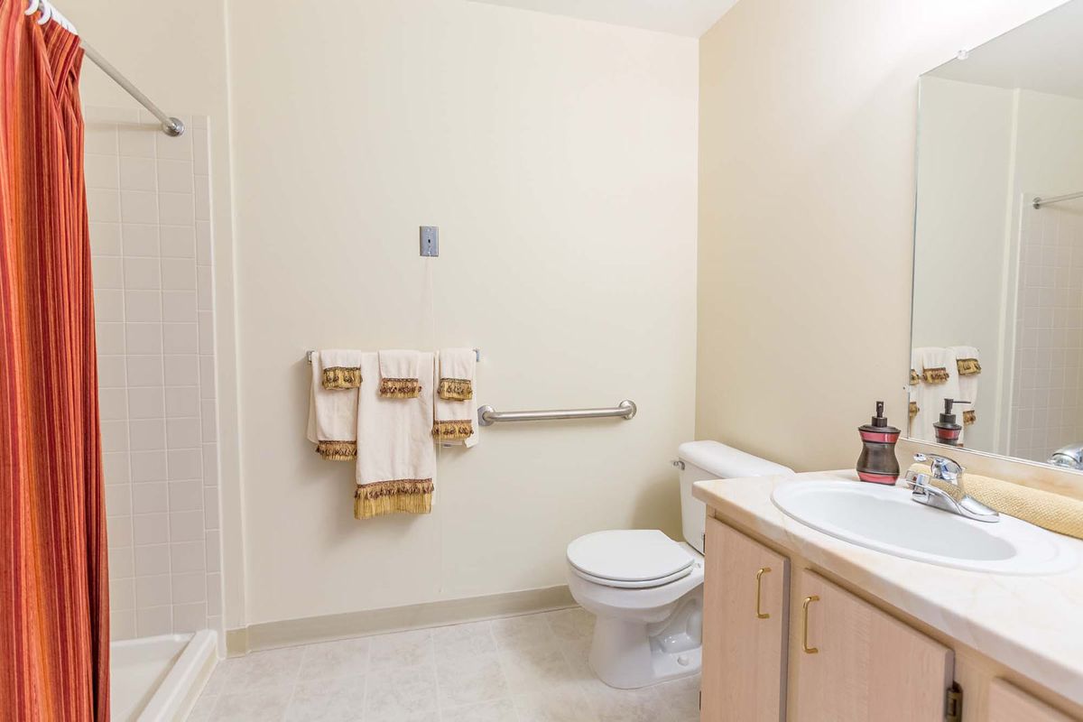 A clean and simple bathroom with a toilet, sink, and neatly arranged towels.