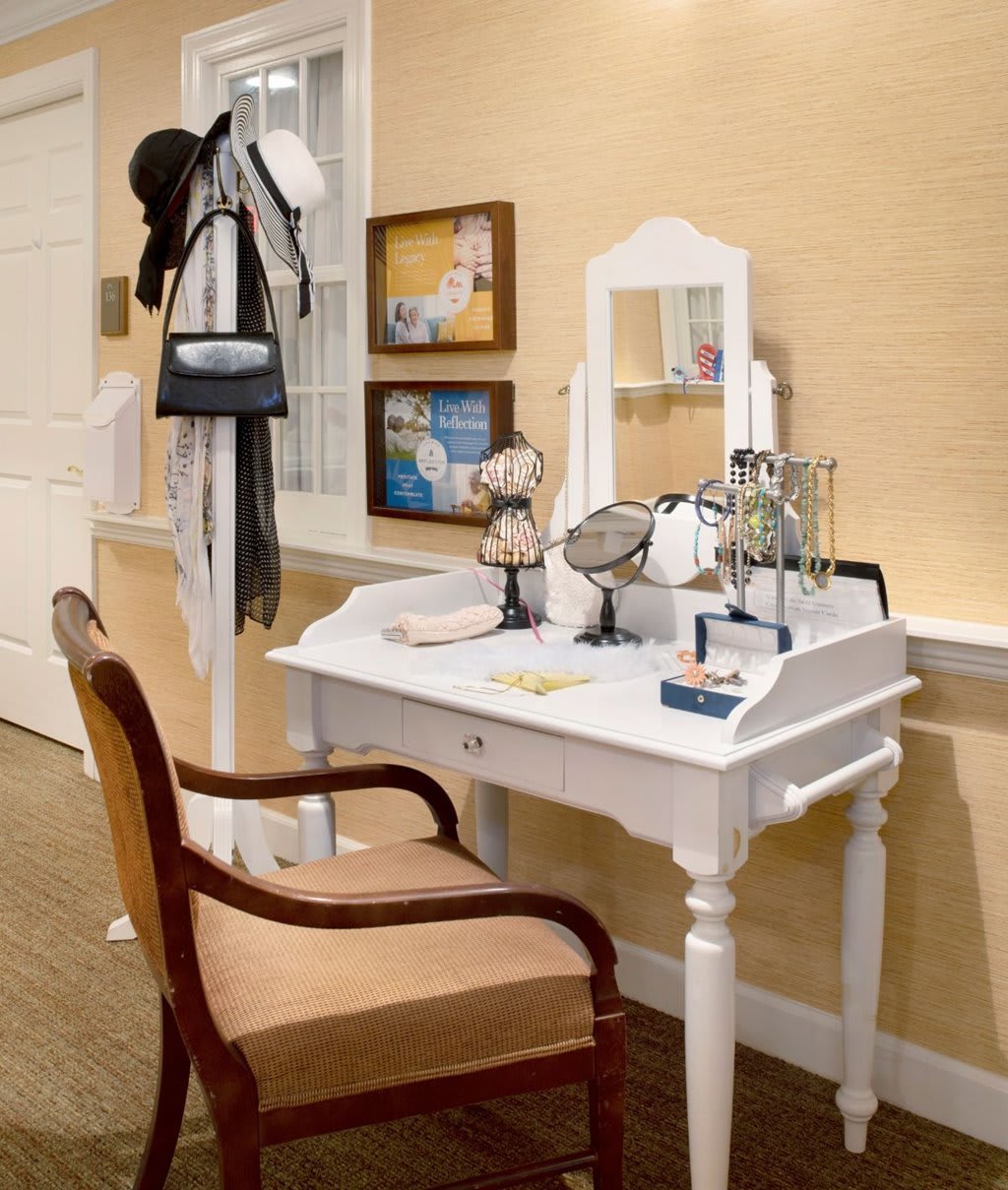 A cozy interior space with a white vanity desk, mirror, and chair surrounded by elegant home decor.
