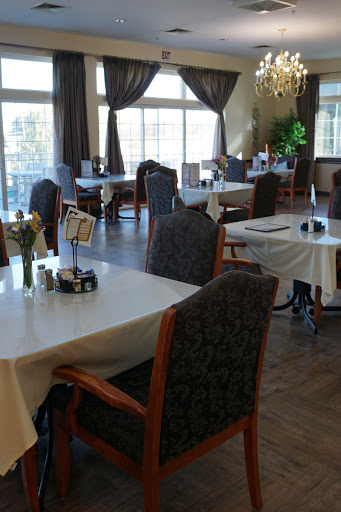 A beautifully arranged dining area with elegant tables and chairs, featuring natural light from large windows.