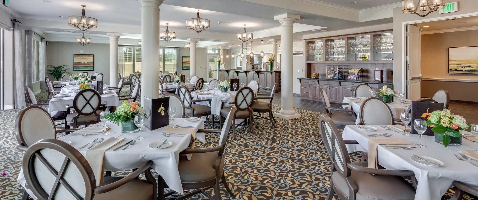 An elegant restaurant dining area with neatly arranged tables and chairs, featuring a stylish carpet and refined decor.