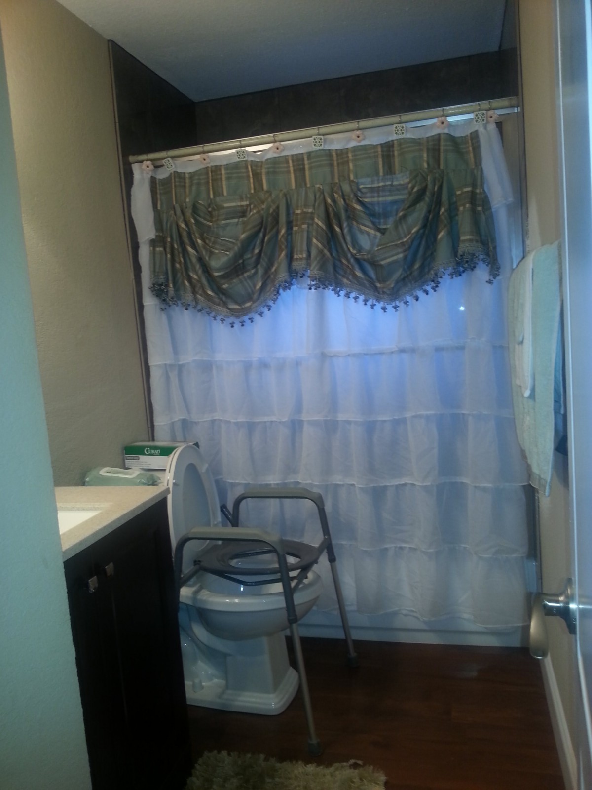 A bathroom with a white shower curtain and an accessible chair.