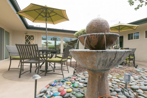 A serene outdoor space featuring a decorative fountain, comfortable seating, and vibrant umbrellas.
