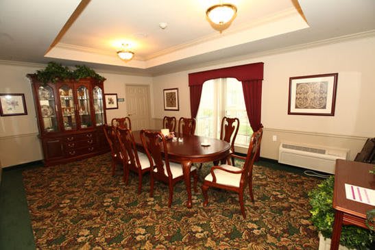 A traditional dining room with a wooden table and chairs, ornate carpet, and elegant curtains.