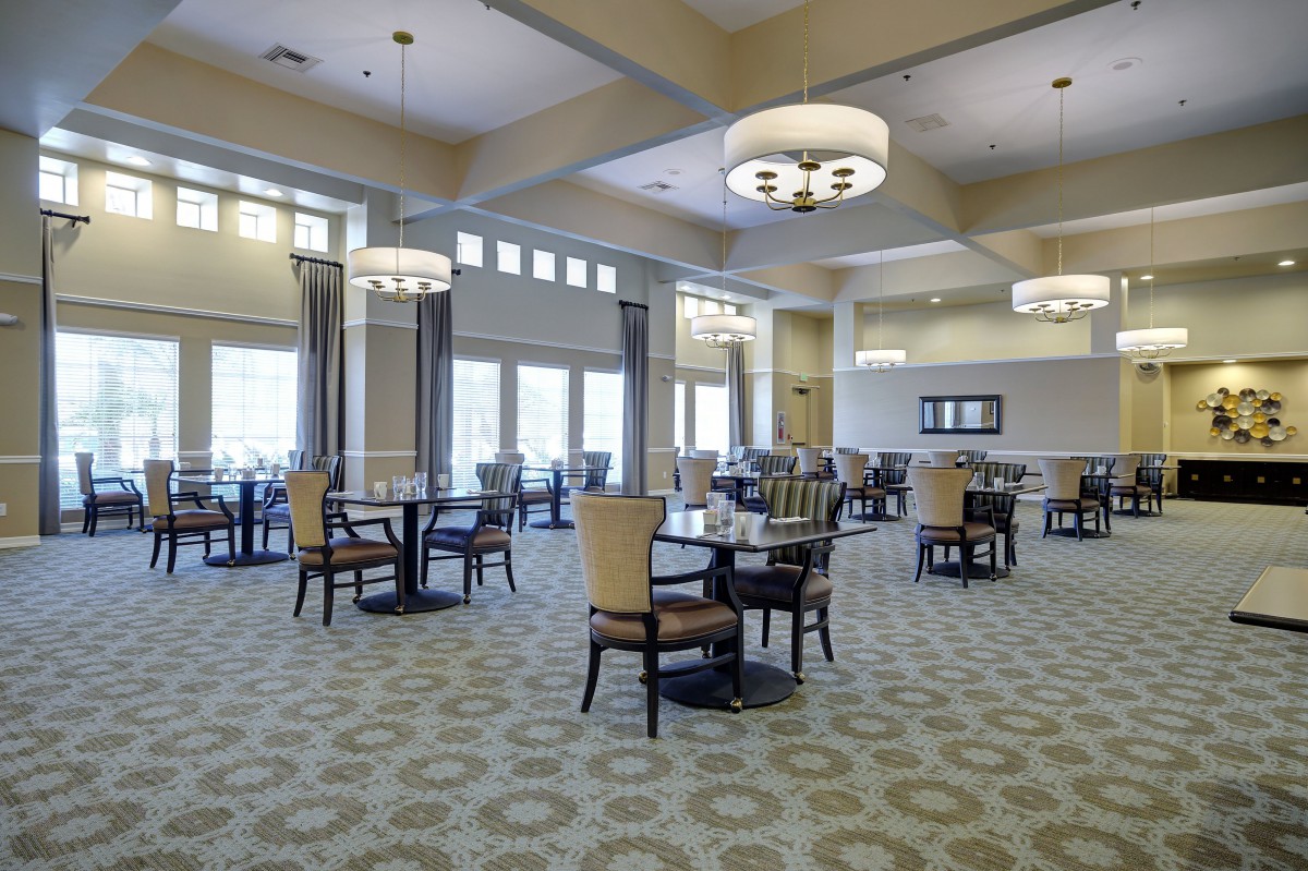 A spacious dining room with elegant chandeliers and neatly arranged tables and chairs.