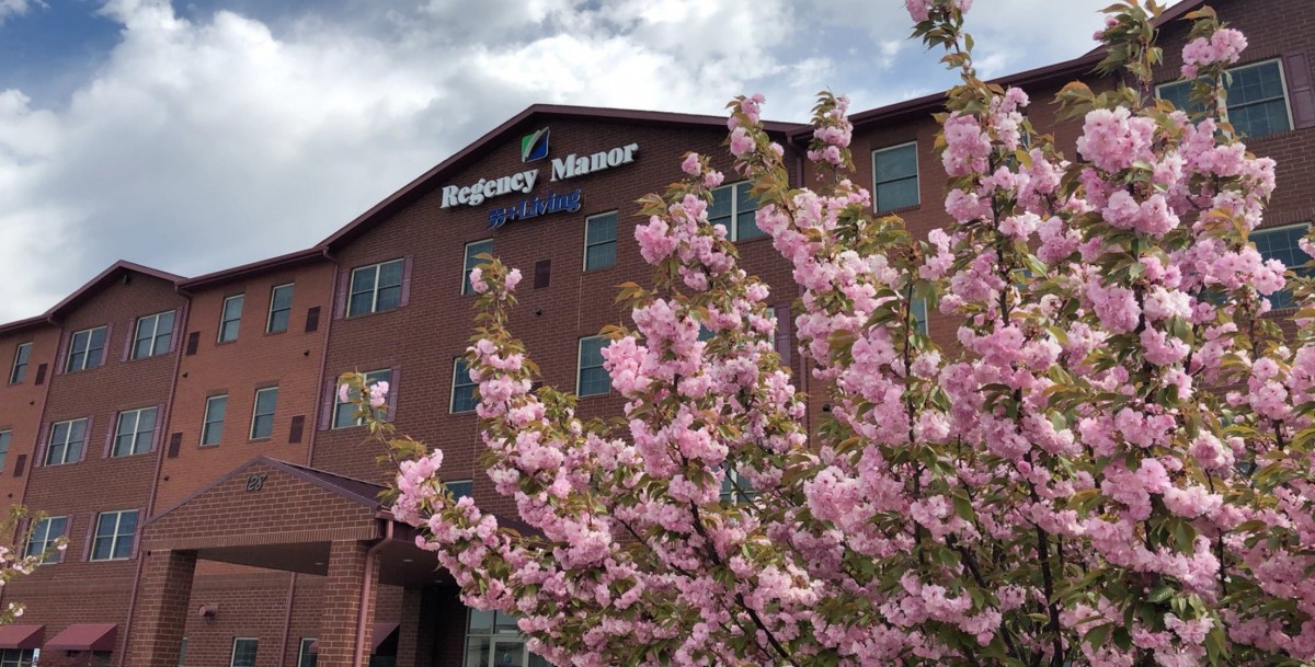 A hotel building with cherry blossoms in the foreground under a cloudy sky.