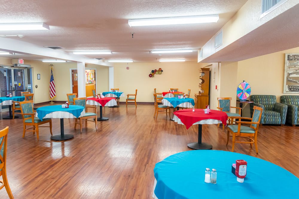 A brightly lit dining area with tables covered in colorful tablecloths.