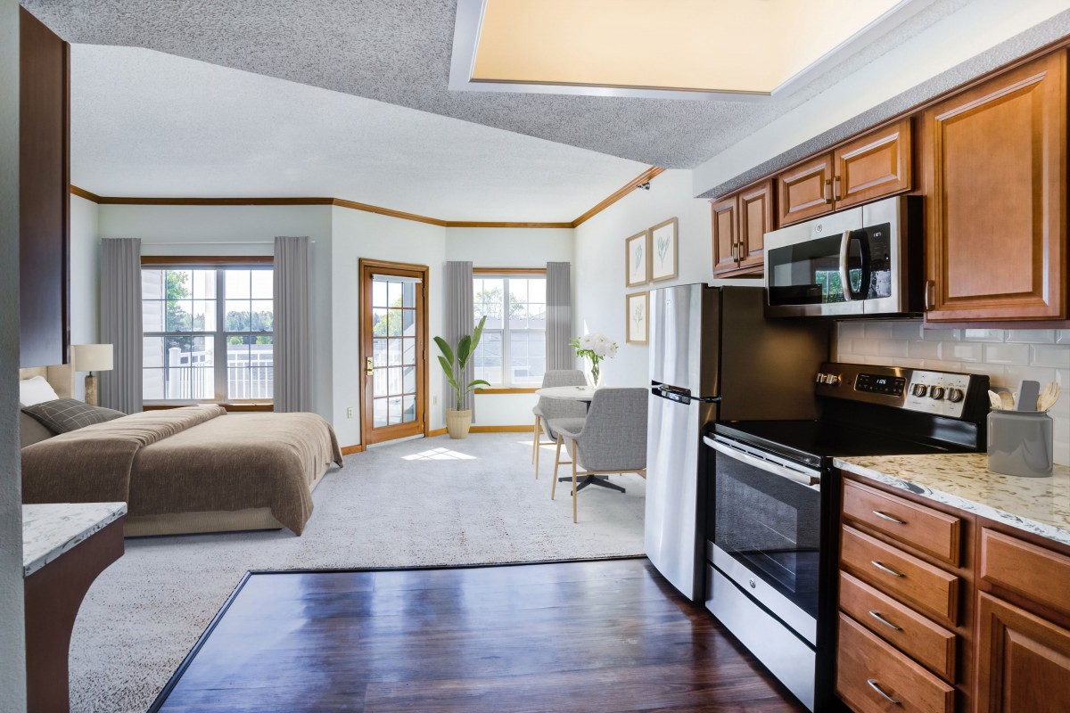 A modern open-plan apartment featuring a kitchen and bedroom area with ample natural light.