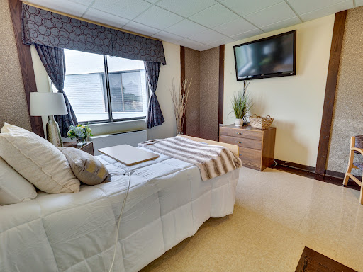 A cozy and modern bedroom featuring a comfortable bed, a television, and natural light from the window.
