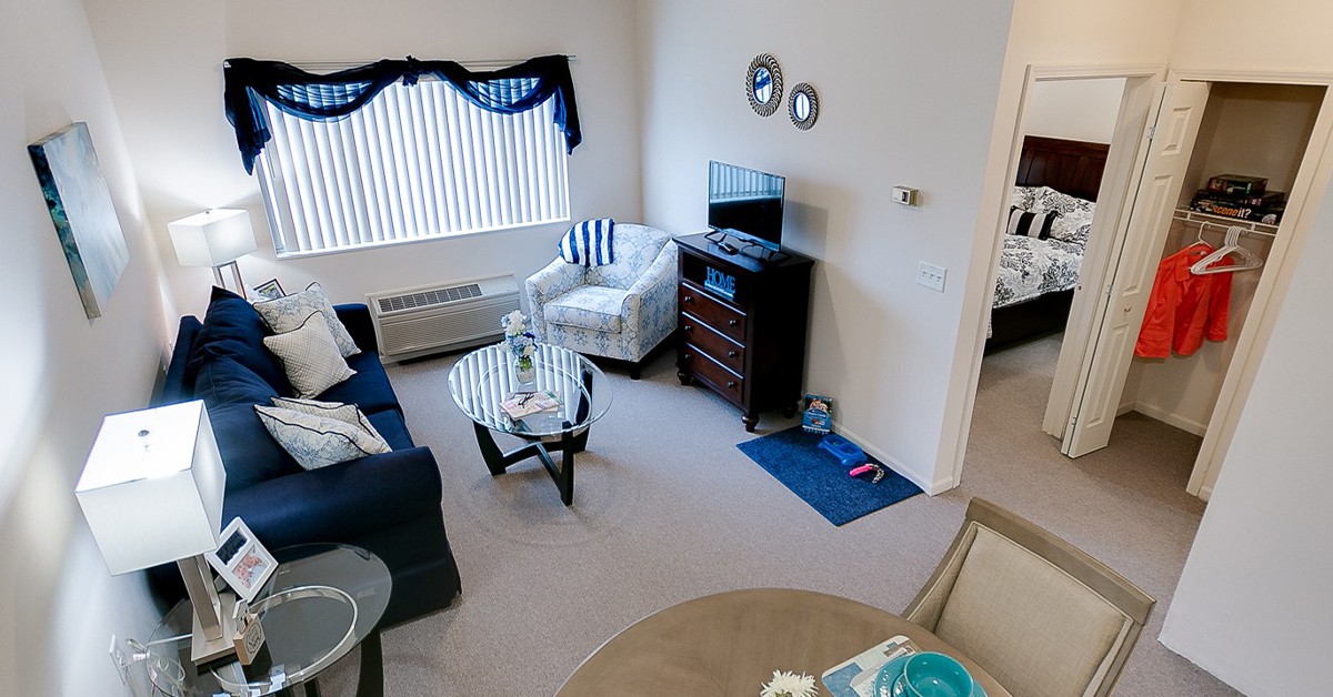 A cozy living room with a sofa, armchair, and a television set.
