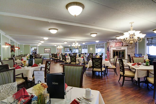 An elegant dining room with neatly arranged tables and chairs, featuring warm lighting and a cozy atmosphere.