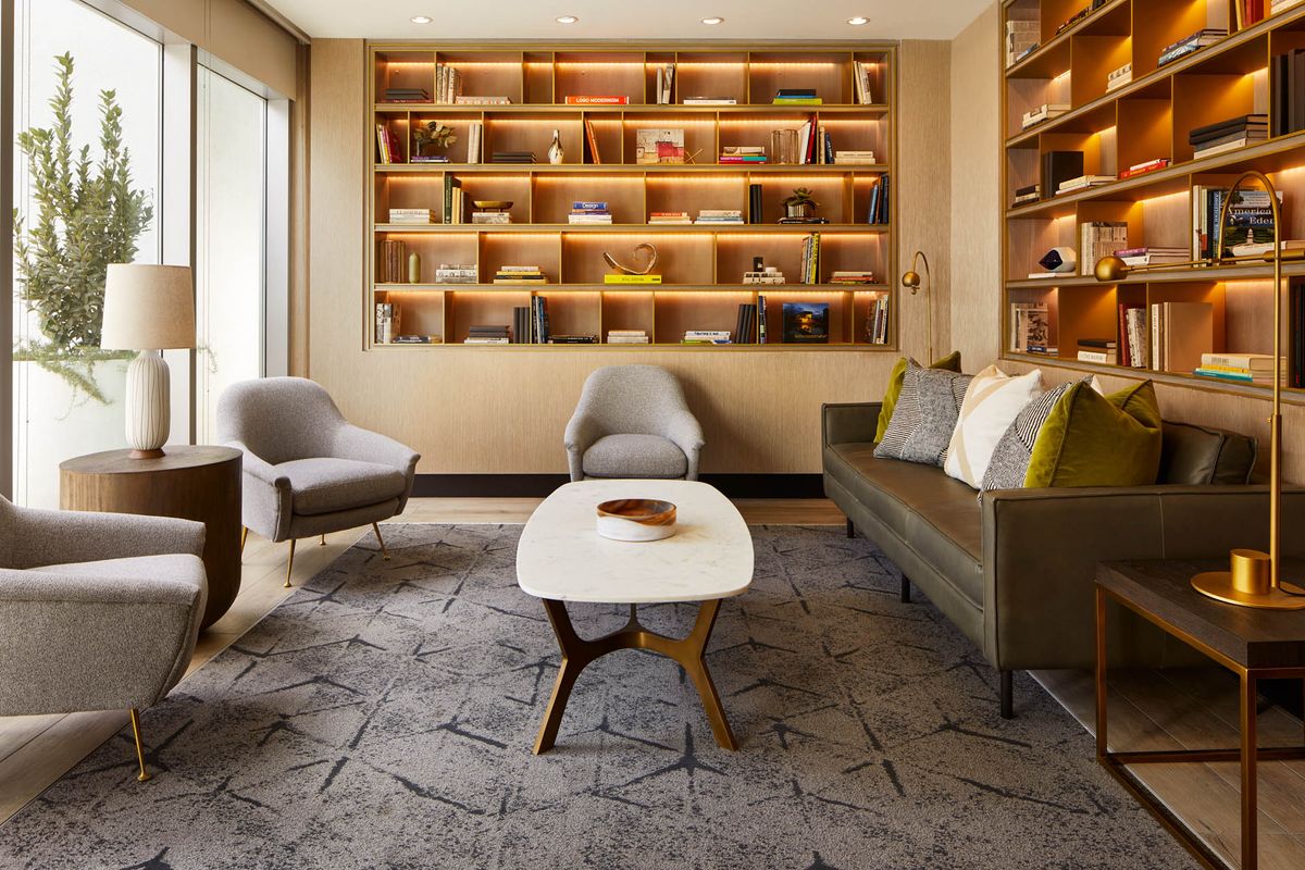 A cozy living room with modern furniture, featuring a large bookshelf and comfortable seating.
