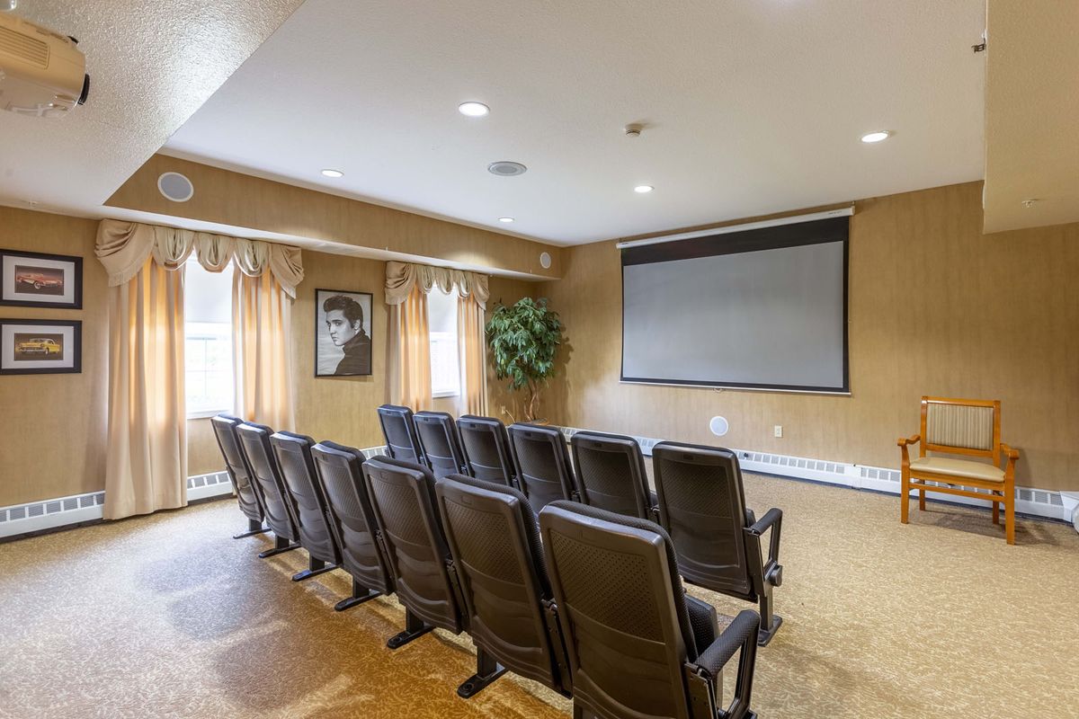 A cozy home theater setup with rows of comfortable seating facing a large screen.