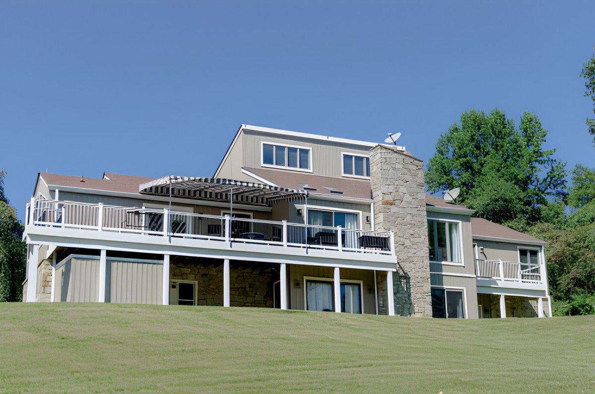 A modern house with a stone facade and large windows, set against a clear blue sky.