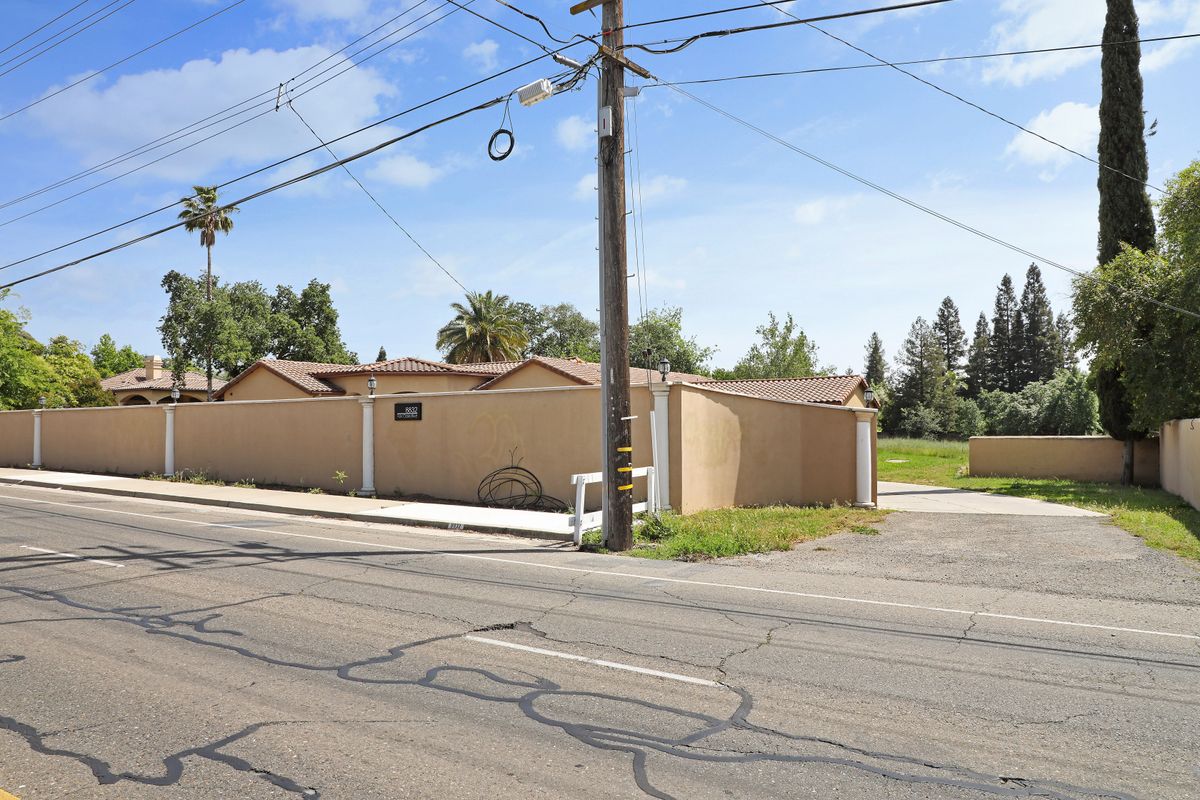 A view of a street intersection with a utility pole and buildings under a clear blue sky.