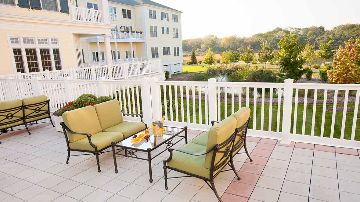 A cozy patio with outdoor seating overlooking a scenic landscape and apartment building.