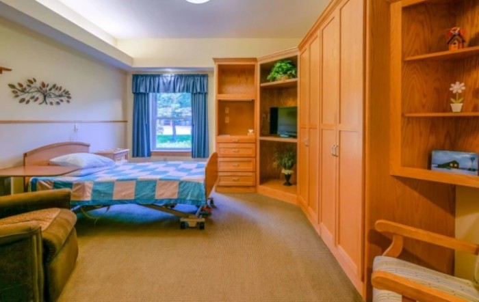 A cozy bedroom with a colorful quilt on the bed and a wooden wardrobe.