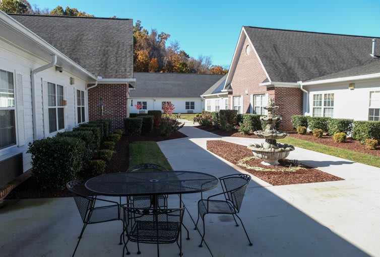 A peaceful courtyard with outdoor seating and a fountain, surrounded by residential buildings.