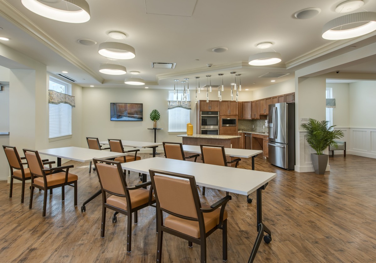 A modern kitchen and dining area with tables, chairs, and wooden flooring.