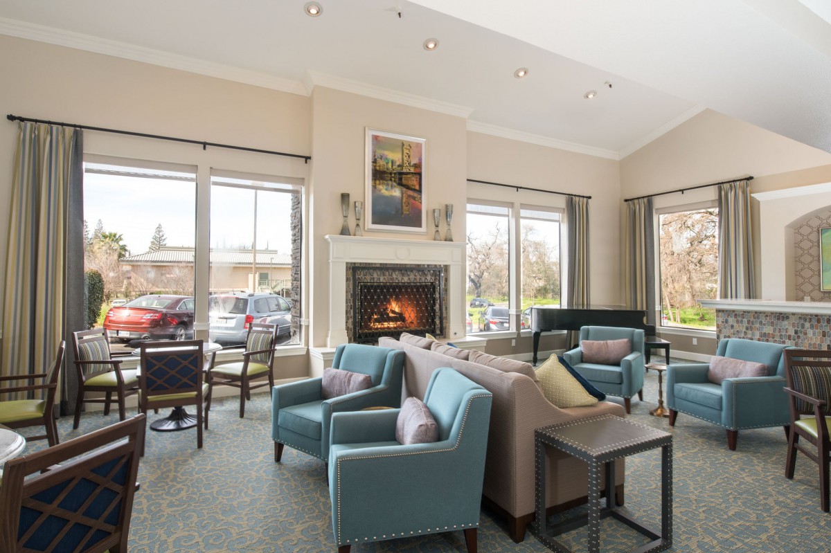 A well-lit living room with comfortable seating arrangements and a cozy fireplace.