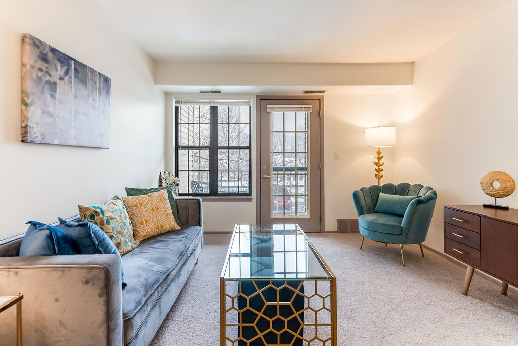 A stylish living room with modern furniture, featuring a comfortable sofa, a unique coffee table, and an elegant armchair next to a floor lamp.