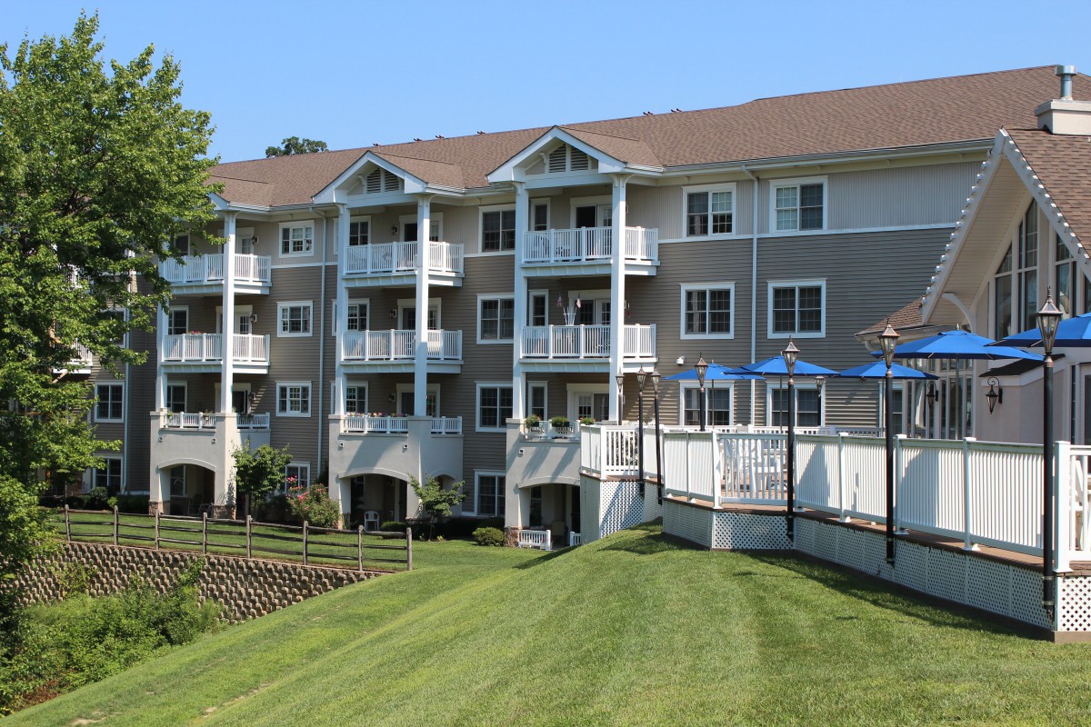 A multi-story residential apartment building with balconies and a well-maintained lawn.