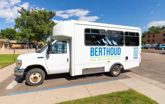 A white shuttle bus with 'Berthoud' written on its side, parked in a sunny outdoor setting.