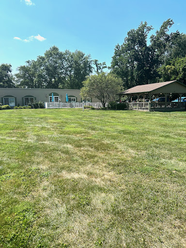 A serene outdoor space featuring a well-maintained lawn and buildings under a clear blue sky.