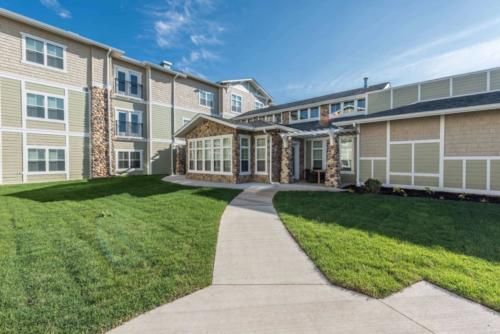 A residential building with a well-maintained lawn and a clear sky.