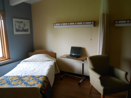 A cozy bedroom featuring a single bed, a desk with a laptop, and a comfortable chair, providing a functional yet inviting space.