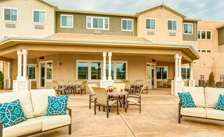 A cozy outdoor patio area with tables and chairs in front of a residential building.