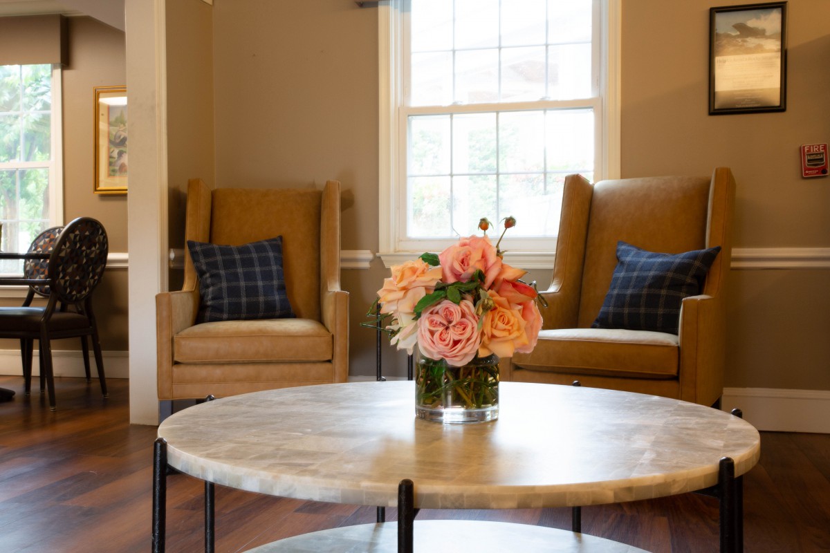 A cozy living room with two chairs and a round table adorned with a floral arrangement.
