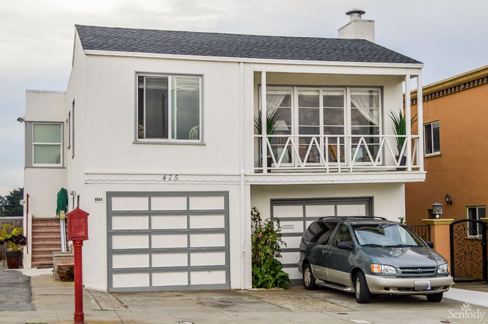 A suburban house with a garage and a car parked in the driveway.