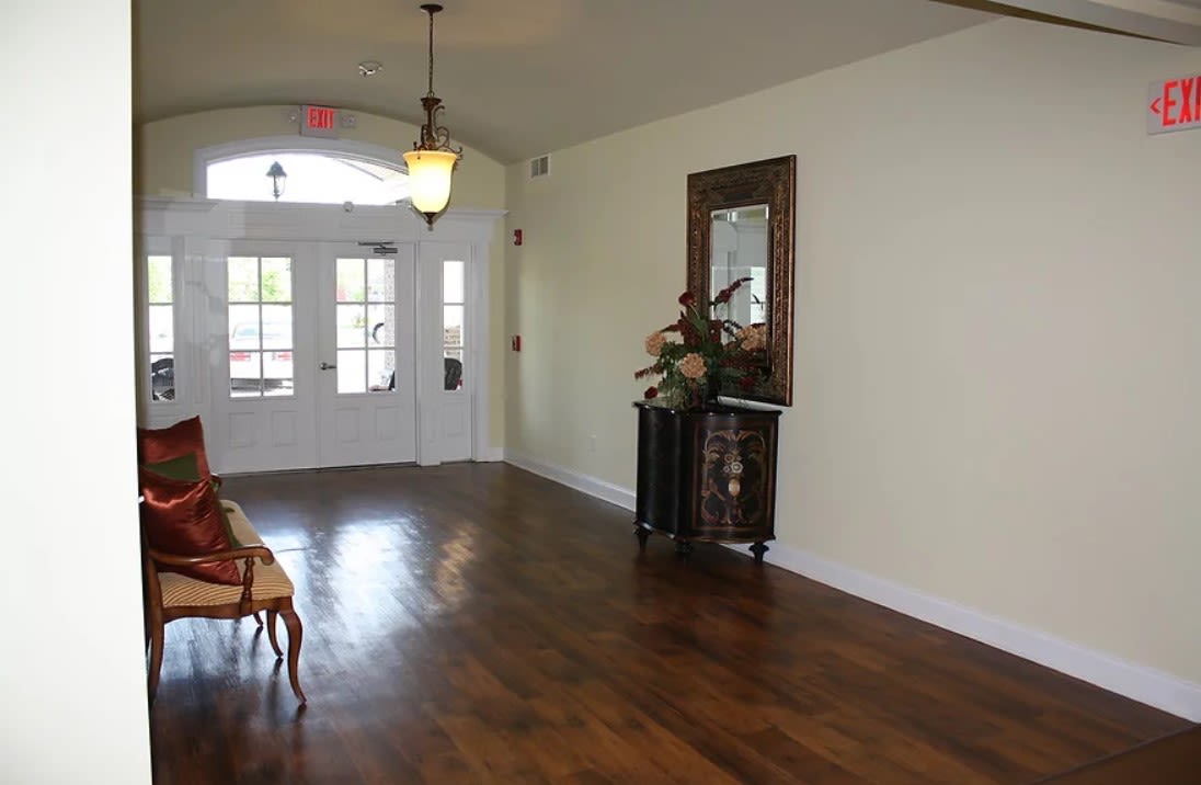A spacious entrance hallway with wooden floors, a decorative table, and a mirror.