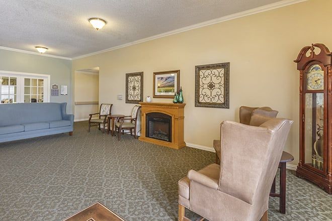A cozy living room with armchairs, a fireplace, and decorative wall art.