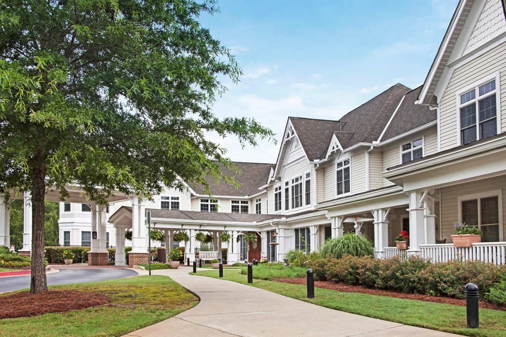 A charming residential building with a well-maintained pathway and lush landscaping.
