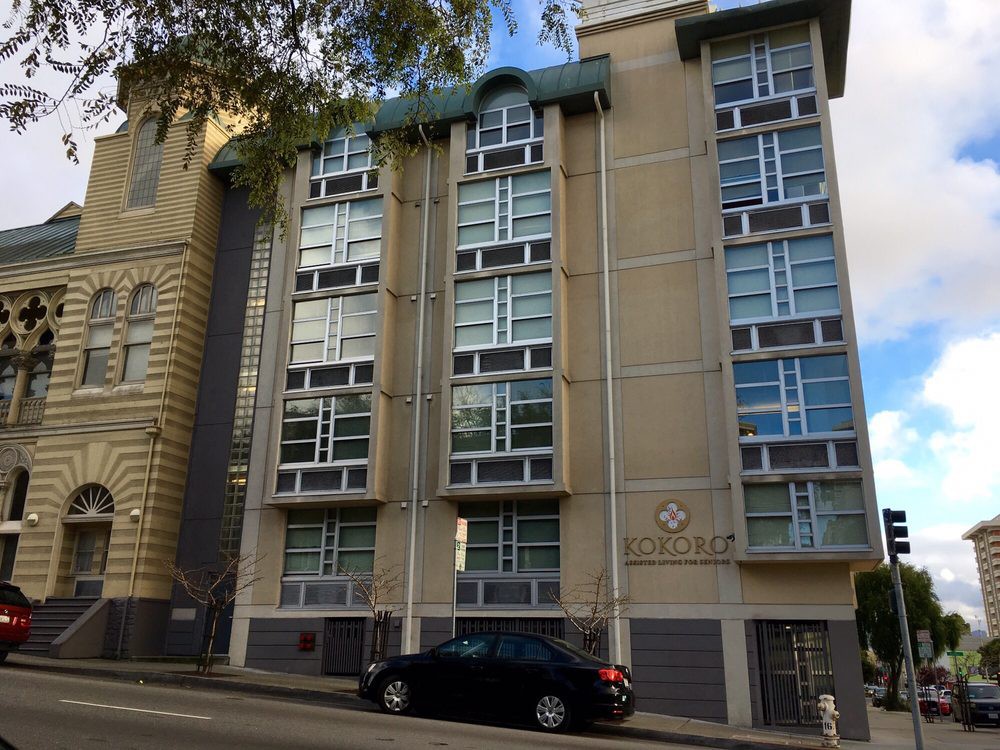 A modern apartment building on a city street with parked cars.
