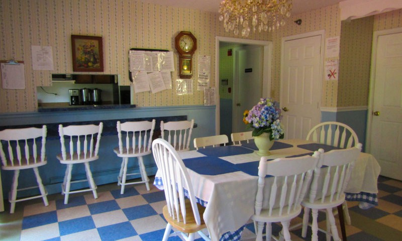 A cozy kitchen with a dining table and chairs, featuring blue and white decor and a checkered floor.